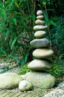 Sculptural tower of large pebbles in a grasses and bamboo garden. Designed by Alan Titchmarsh at Barleywood, Hampshire.
