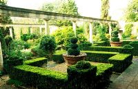 Behind the colonnade of the Great Terrace is a formal garden of box hedges framing pots from a villa near Siena - Iford Manor, Bradford-on-Avon, Wiltshire