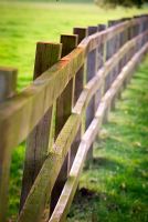 Three bar wooden fence receding to the distance