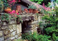 Old stone wall with terracotta pots and horseshoes