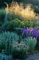 The dry Gravel Garden in late spring at Beth Chatto's Garden, Essex. Mixed planting of perennials including Pulsatilla, Nepeta, Euphorbia, Verbascum and Stipa gigantea