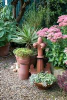 Phalaris arundinacea, Yucca variegata , Sedum 'Herbstfreude', Sedum 'Autumn Joy' chimney pots and coping tiles from Victorian roof