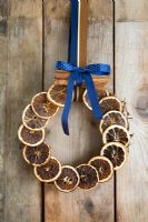 Festive Christmas wreath of dried orange slices and a bundle of cinnamon sticks on wooden background