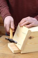 Step by step 5 of making a bat box from a single length of timber - Hammering in nails to secure the lid of the wooden box