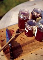 Jars of jam on chopping board on table