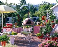 Seating area on paved patio with pizza oven in background