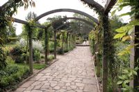 Wooden arch Pergola with Wisteria and Clematis, crazy paving of Yorkstone - Sexby Garden, Peckham Rye Park, London, heritage lottery fund
