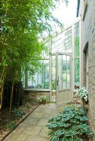 Lean to conservatory with Hostas, bamboos and rope top victorian edging tiles outside