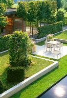 This aerial view reveals the layers and divisions of this otherwise flat Belgium garden. Pleached hornbeams and hedging screens the garden room from the dinning terrace. Limestone blocks raise and boarder the lawn.