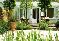 From this pale green, furnished garden apartment, sliding doors open onto an interior courtyard. The space is divided by pleached hornbeams and boarders of delicate perennials.