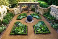 'Dark Planet' pebbled sculpture in formal walled private garden
