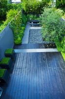 Small contemporary garden with black painted deck with grey pebbled patio, black marble table and Catalpa on the right - London