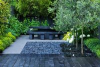Small contemporary garden with black deck and grey polished pebbles, Catalpa set into squares underplanted with Ophiopogon and black marble table - London