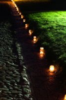 Tealights in jam jars lighting up a path  