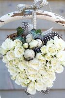 White rose heart wreath with speckled eggs, tied to the back of a rustic chair 