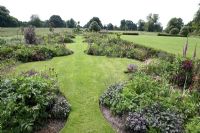 Keyhole shaped beds with mixed planting, garden surrounded by English countryside - Narborough Hall