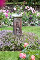 Sundial in a cottage garden with thyme and roses