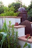 A Moroccan inspired garden with drought tolerant planting - Rendered wall with clay tiles, Moroccan lantern and small clay tea light holders