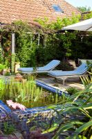 Moroccan inspired garden with drought tolerant planting tiled pond and wooden steamers on the terrace