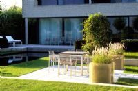 White fibreglass planters of Pennisetum beside the dining area and the swimming pool - Belgium