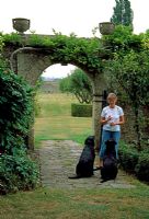Woman with her two black Labrador dogs - The Monastery Garden