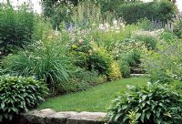 Delphiniums grow in the herbaceous cottage borders - Les Jardins de Quatre-Vents, Quebec