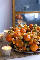Christmas wreath with golden baubles, tealights, kumquats and satsumas, mirror in background
