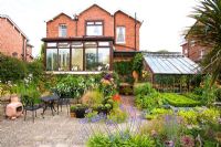 Rear of large detached house with conservatory and well planted garden