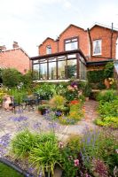 Rear of large detached house with conservatory and well planted garden