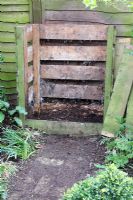 Turning out compost in Spring, brick path leading to compost bin in shady corner of town garden - Step by step bottom layer of compost bin