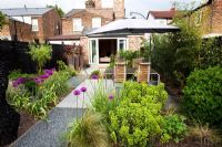 Patioa area with Euphorbia robbiae and Allium 'Purple Sensation' - Small urban garden in London