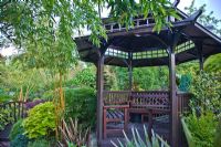 Pergoda with mature trees and shrubs in oriental themed garden at Four Seasons, NGS garden, Staffordshire