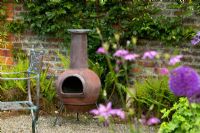 Chiminea in English country garden, with ferns and brick wall