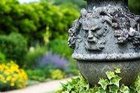Pan face on a stone urn at Waterperry gardens, Oxfordshire, England