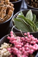 Bay leaves, cinnamon sticks and peppercorns still in their pink outer case