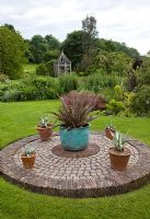 Garden feature circle of cobbles with containers borders of herbaceous perennials lawns beautiful green oak gazebo and mature trees - Woodpeckers, Warwickshire