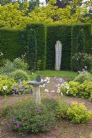 Scented garden with herbaceous perennials, hedging with wooden sculpture of St Fiacre and ornate sundial with butterfly feature - Woodpeckers, Warwickshire
