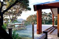 Large wooden deck with glass railings maximising the sea view. Pohutukawa trees and Manuka surround