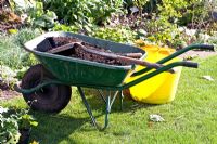 Wheelbarrow of compost, spade and buckets beside border - Birmingham Botanical Gardens