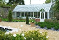 A Victorian style greenhouse is situated on a south facing wall within the Secret Garden, a blend of Islamic and Mediterranean influences. Private garden, Dorset, UK