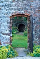 View through gateway to the walled Garden and the Grotto. Alchemilla mollis edges the gateway - Glansevern Hall Gardens, Welshpool, Wales in July