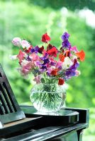 Old fashioned sweet peas in a glass vase on a piano