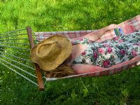 Woman relaxing in hammock with straw hat and flowery dress