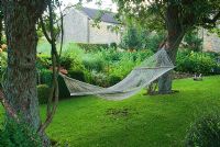 Two old fruit trees support a hammock and various swings and ladders for the girls to play on. Yews Farm, Martock, Somerset, UK
