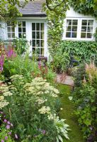 Borders of herbaceous perennials with flowers in profusion, packed into an idyllic English cottage garden, Grafton Cottage, NGS, Barton-under-Needwood Staffordshire