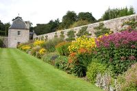 Late summer herbaceous border along wall with trained apple trees, leading to pavilion in one corner of the Great Garden at Pitmedden, Aberdeenshire - The National Trust of Scotland 