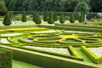 Looking down on the Great Garden at Pitmedden with colourful Buxus - Box -edged parterres infilled with annuals, Taxus baccata - Yew - pyramids and herbaceous borders with trained apples on the walls behind -  The National Trust for Scotland