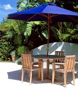 Wooden seating area with blue parasol with tropical planting
