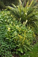 Border with Phormium, Corydalis cheilanthifolia, Geranium and Erythronium 'Pagoda' at 'Briarfield', Cheshire