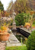 Canal garden with terra cotta pots and statuary in autumn at Wilkins Pleck (NGS) Whitmore near Newcastle-under-Lyme in North Staffordshire